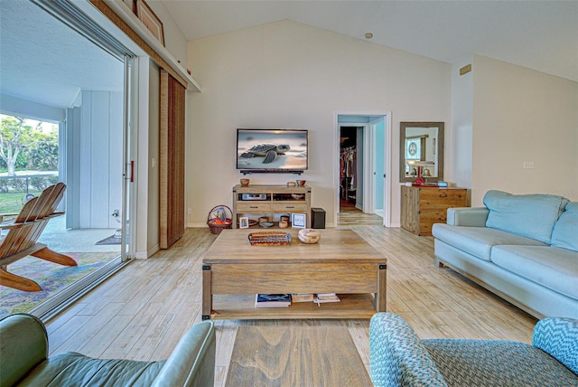 living area with high vaulted ceiling, light wood-type flooring, and baseboards