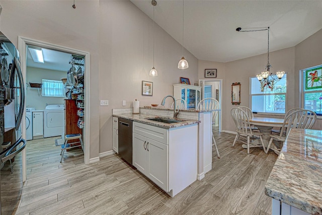 kitchen featuring a peninsula, a sink, light wood-style floors, dishwasher, and washing machine and clothes dryer