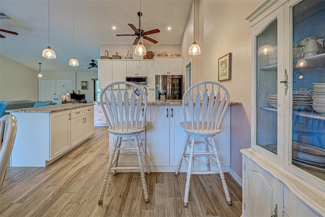 kitchen with a ceiling fan, light wood-type flooring, stainless steel fridge, and white cabinetry