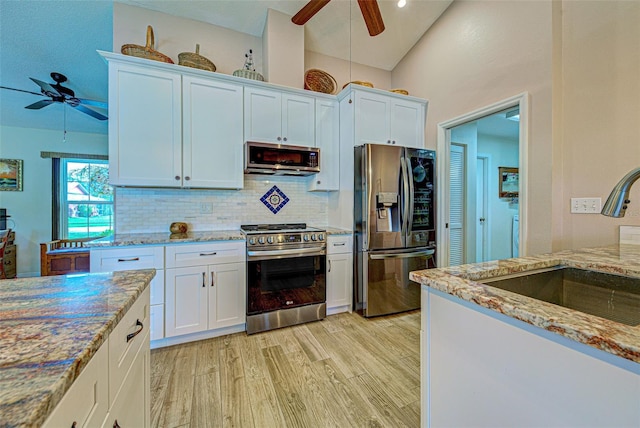 kitchen with tasteful backsplash, lofted ceiling, appliances with stainless steel finishes, light wood-type flooring, and a sink