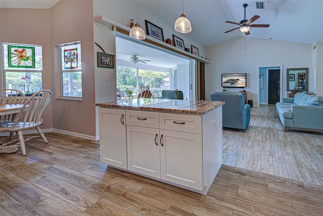 kitchen with visible vents, white cabinets, light stone counters, open floor plan, and light wood-type flooring