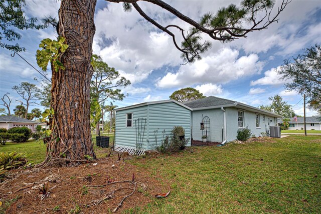 back of house with cooling unit, a lawn, and stucco siding