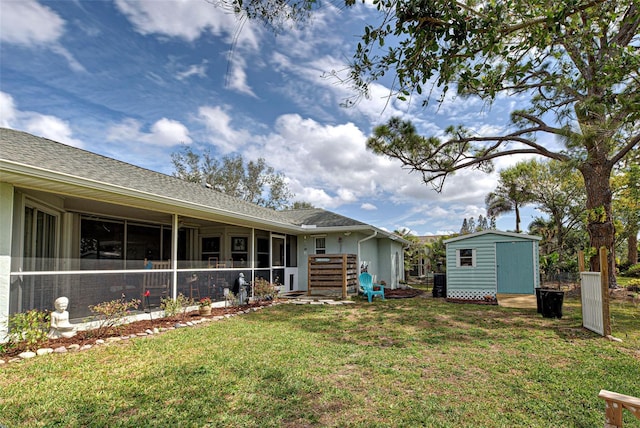 rear view of property featuring a shingled roof, a lawn, a sunroom, an outbuilding, and a shed