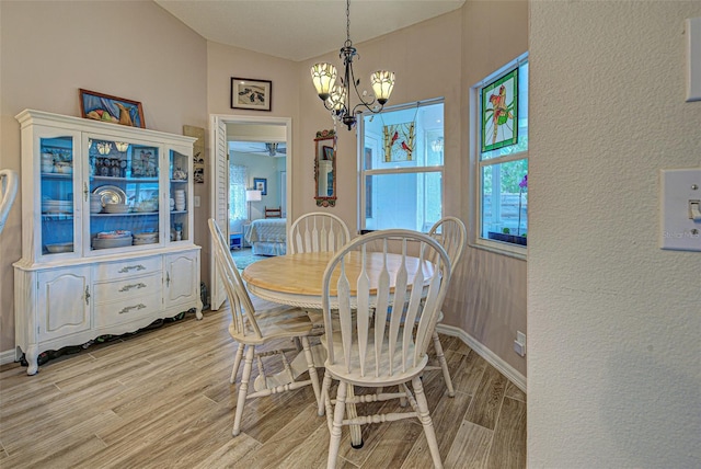 dining space featuring baseboards, light wood-type flooring, and an inviting chandelier