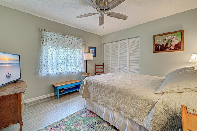 bedroom featuring a closet, a ceiling fan, a textured ceiling, wood finished floors, and baseboards