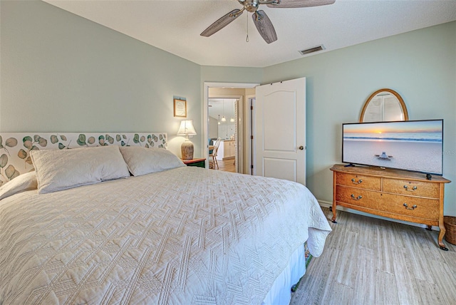 bedroom featuring ceiling fan, wood finished floors, and visible vents