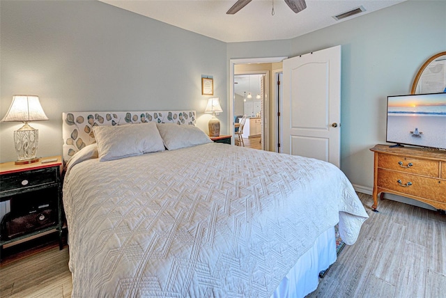 bedroom featuring ceiling fan, wood finished floors, visible vents, and baseboards