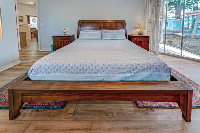 bedroom featuring access to outside, baseboards, and wood finished floors