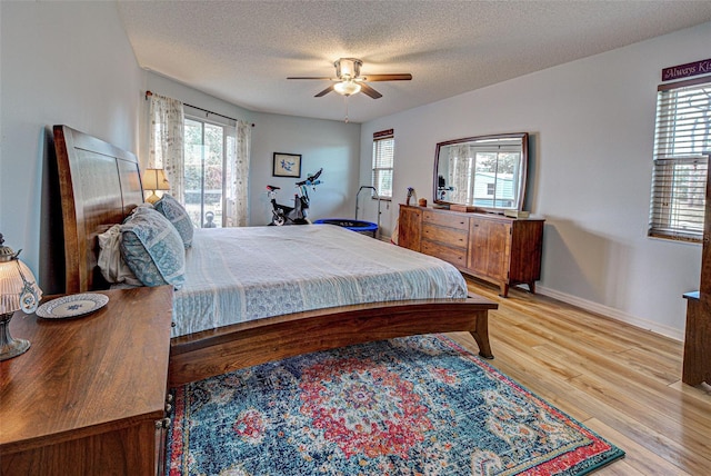 bedroom with light wood-type flooring, multiple windows, ceiling fan, and baseboards