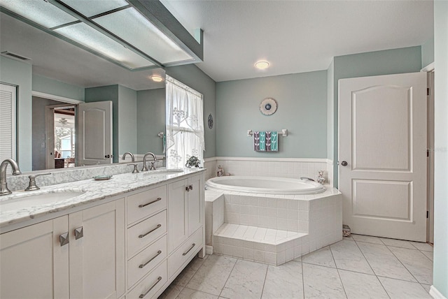 full bathroom with a bath, double vanity, visible vents, and a sink