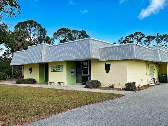 view of property featuring metal roof and a front yard