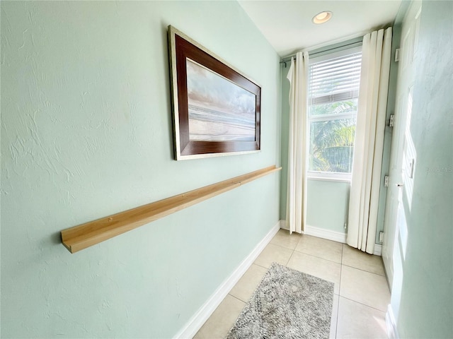 hallway featuring baseboards and light tile patterned flooring