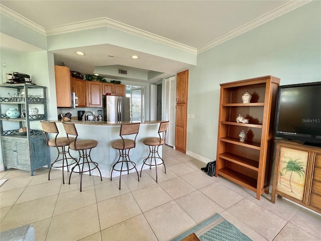 kitchen featuring a breakfast bar, a peninsula, light tile patterned flooring, and appliances with stainless steel finishes