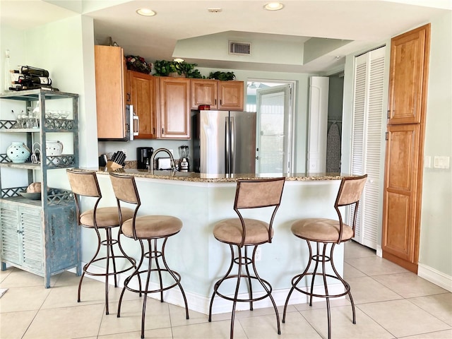 kitchen featuring visible vents, appliances with stainless steel finishes, a breakfast bar, and a peninsula