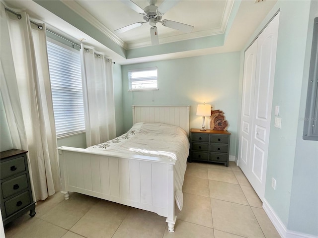 bedroom featuring a ceiling fan, a tray ceiling, light tile patterned flooring, crown molding, and baseboards