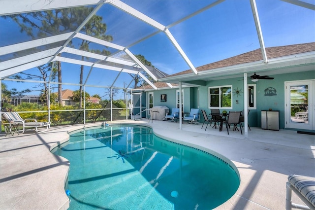 outdoor pool with a lanai, a ceiling fan, and a patio