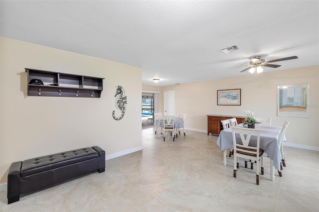 dining room with a textured ceiling, baseboards, visible vents, and ceiling fan