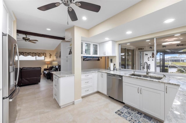 kitchen featuring a sink, open floor plan, stainless steel appliances, white cabinets, and light stone countertops