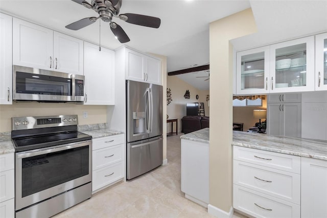 kitchen with glass insert cabinets, light stone countertops, white cabinets, stainless steel appliances, and a ceiling fan