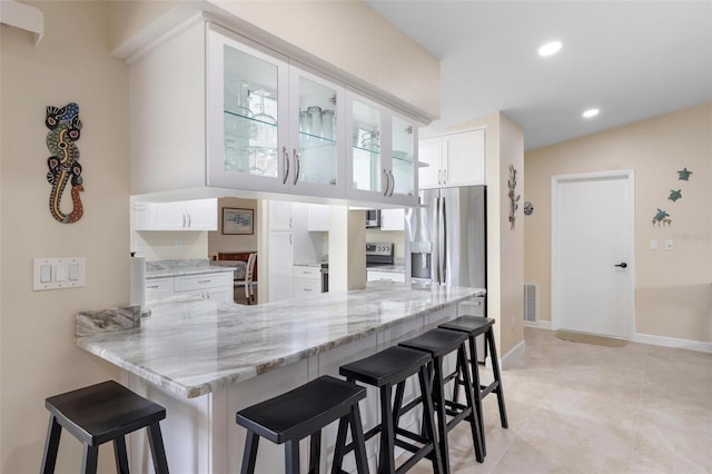 kitchen with white cabinets, a peninsula, a breakfast bar, and glass insert cabinets