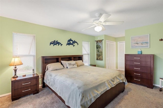 bedroom featuring baseboards, two closets, a ceiling fan, and carpet