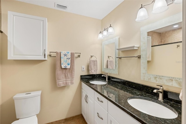 bathroom with double vanity, toilet, visible vents, and a sink