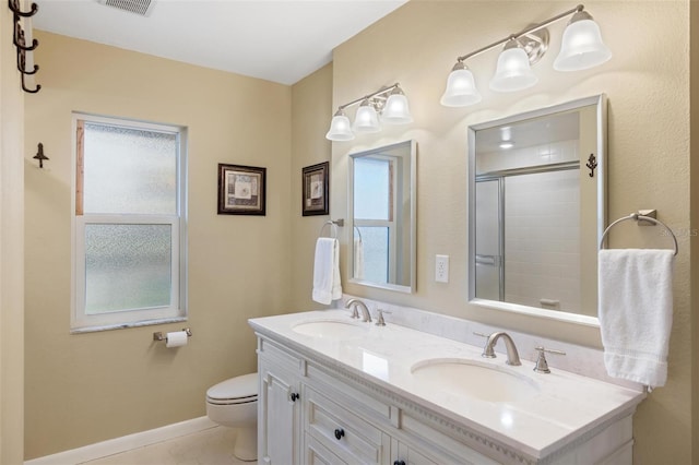 bathroom with tile patterned floors, toilet, tiled shower, and a sink