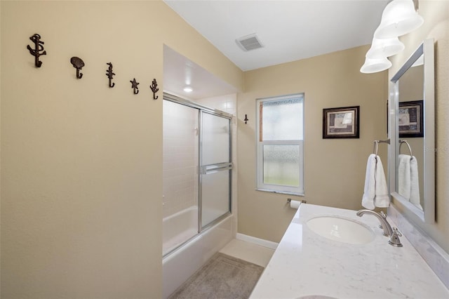 bathroom featuring visible vents, baseboards, shower / bath combination with glass door, and vanity