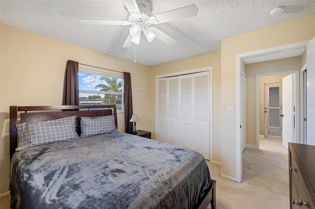 bedroom featuring baseboards, ceiling fan, light carpet, a closet, and a textured ceiling