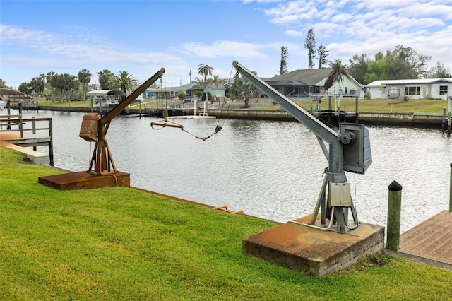 view of dock with boat lift, a residential view, a yard, and a water view