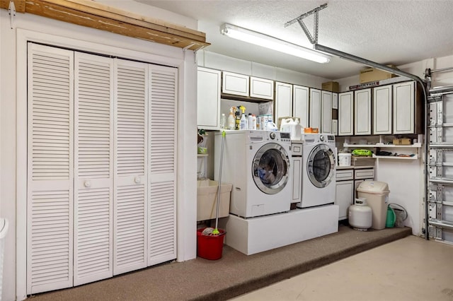 washroom featuring a garage, cabinet space, separate washer and dryer, and a textured ceiling