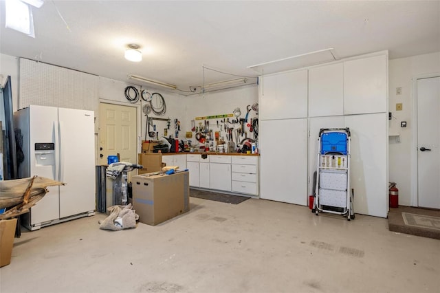 garage featuring a workshop area and white refrigerator with ice dispenser