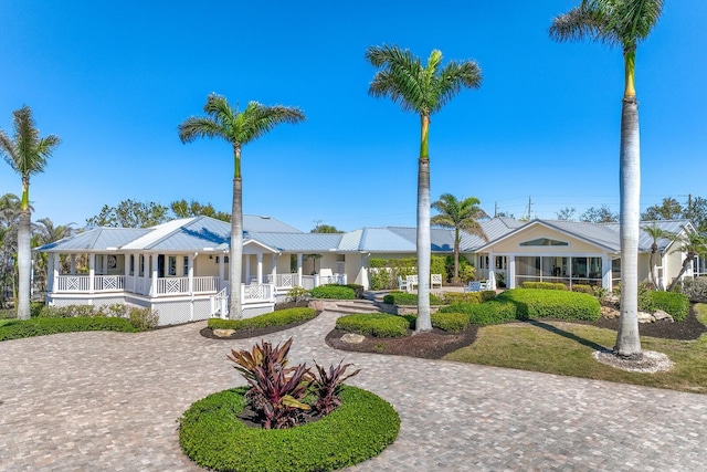 view of front of property featuring curved driveway, covered porch, and metal roof