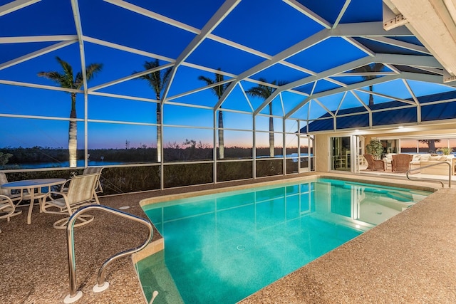 pool at dusk with an outdoor pool, glass enclosure, and a patio