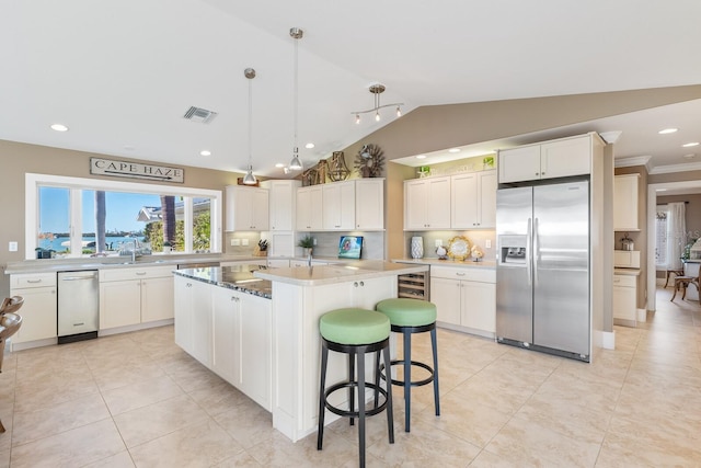 kitchen featuring visible vents, lofted ceiling, stainless steel fridge with ice dispenser, white cabinets, and a center island