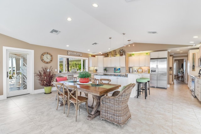 dining room with light tile patterned flooring, visible vents, and vaulted ceiling