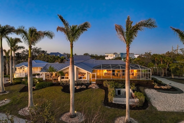 back of house at dusk with a standing seam roof, a lanai, and metal roof