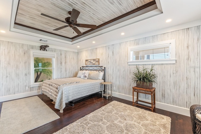 bedroom featuring a tray ceiling, wood finished floors, and baseboards