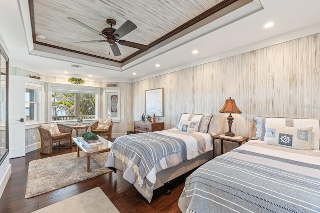 bedroom featuring a raised ceiling, recessed lighting, wood finished floors, and ornamental molding