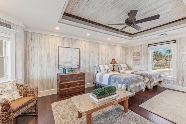 bedroom with hardwood / wood-style floors, a raised ceiling, baseboards, and visible vents