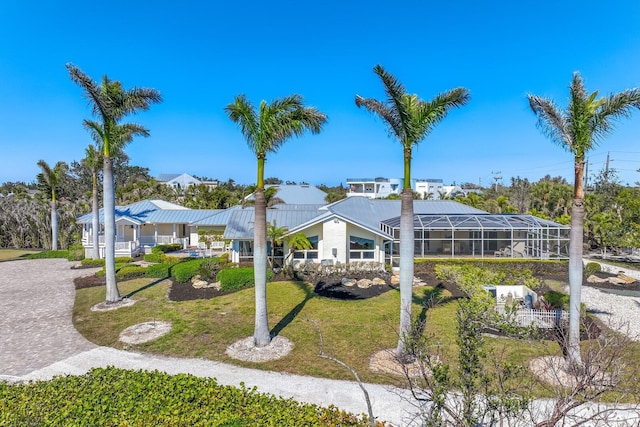 view of front of house with metal roof, glass enclosure, and a front lawn