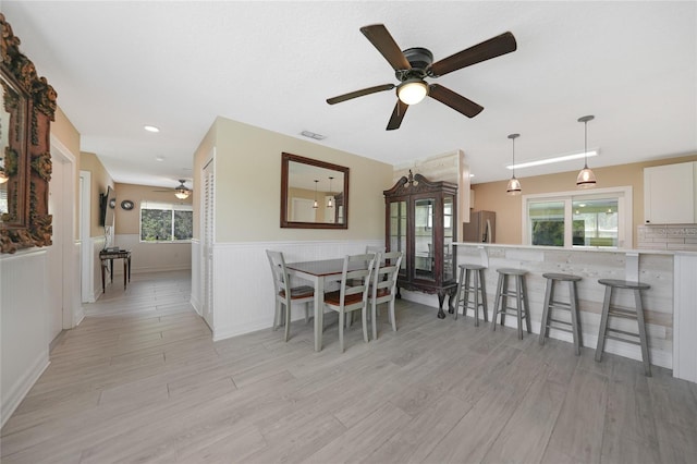 dining room featuring a wainscoted wall, a healthy amount of sunlight, and a ceiling fan