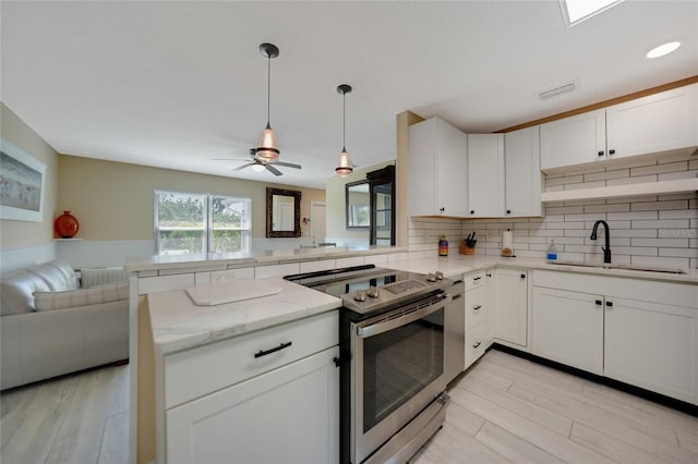 kitchen with open floor plan, light stone counters, a peninsula, electric range, and a sink