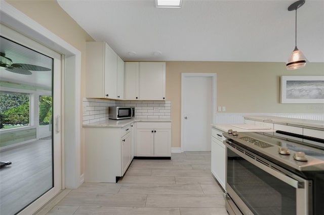 kitchen with tasteful backsplash, wood finish floors, stainless steel appliances, hanging light fixtures, and white cabinetry