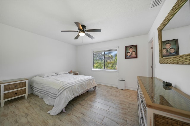 bedroom featuring visible vents, light wood-style flooring, baseboards, and a ceiling fan