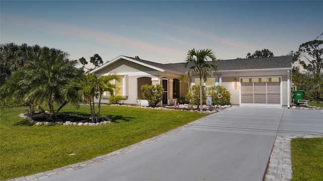 single story home featuring stucco siding, an attached garage, driveway, and a lawn