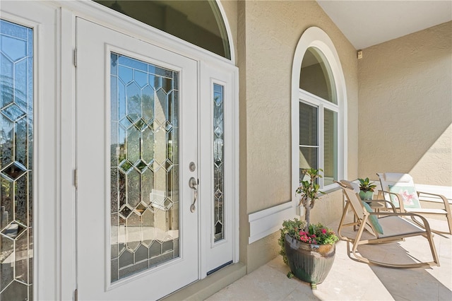 property entrance with covered porch and stucco siding