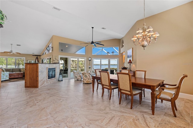 dining room featuring plenty of natural light, ceiling fan with notable chandelier, a fireplace, and visible vents