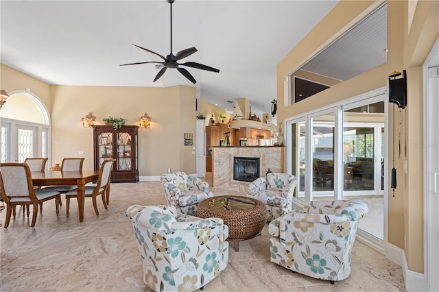 living room with baseboards, ceiling fan, vaulted ceiling, and a tile fireplace