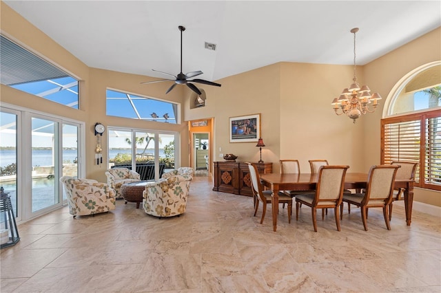 dining area featuring a wealth of natural light, visible vents, a water view, and a towering ceiling